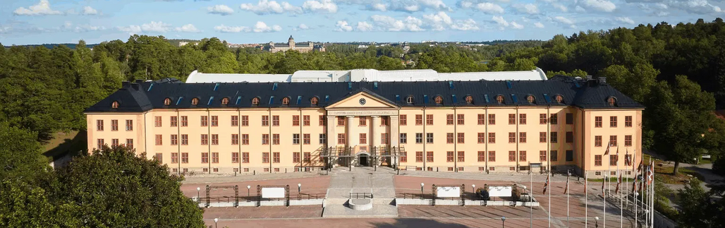 Flygfoto över stort klassiskt byggnadskomplex omgivet av skog